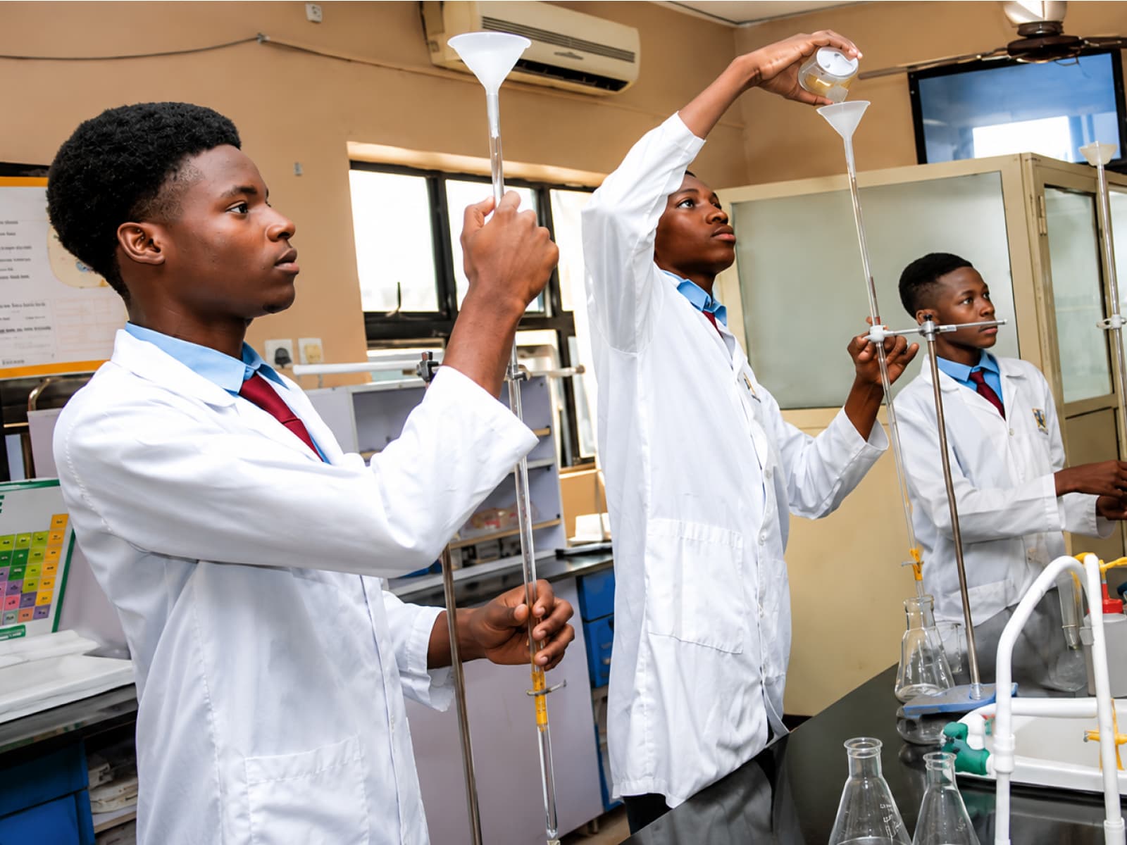 Three Sanctum Startup College students conducting a collaborative science experiment in the school laboratory, Isheri North, Lagos